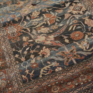 Traditional rug displaying dark blue, grey, and terracotta floral patterns with complex borders.