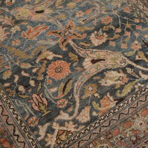 Close-up of a rug featuring a faded navy blue field with detailed terracotta, beige, and olive floral motifs.