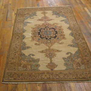 Traditional beige rug with blue and rust medallion sits on distressed wood flooring.