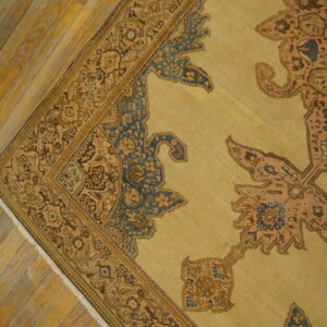 Close-up of a traditional tan and brown rug featuring blue accents on distressed wood flooring.