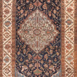 A traditional navy and rust patterned rug with light blue accents rests on wide plank wood flooring.