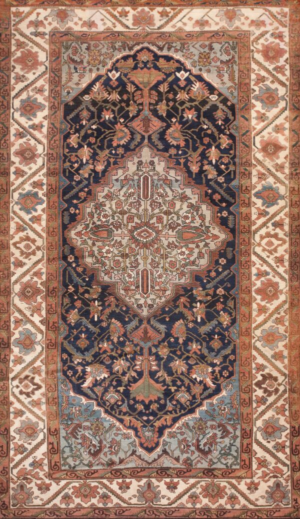 A traditional navy and rust patterned rug with light blue accents rests on wide plank wood flooring.