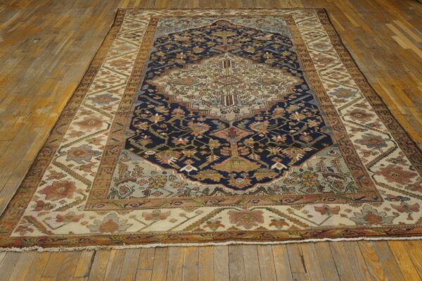 Intricate navy and ivory medallion pattern rug featuring muted blue and pink accents on wood planks.