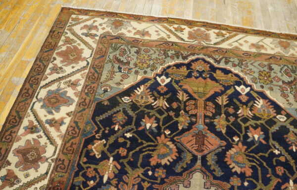 Traditional rug featuring a navy field, ivory border, and rust/green patterns on distressed wooden plank floor.