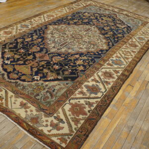 Blue and cream patterned rug with rust and sage accents lies diagonally on light brown wood flooring.