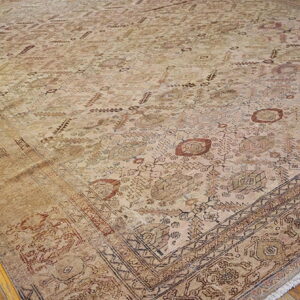 Tan area rug with faded geometric patterns in brown and rust, laid on hardwood flooring.