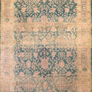 Ornate, faded blue and gold floral rug with pink accents covers a worn wooden plank floor.