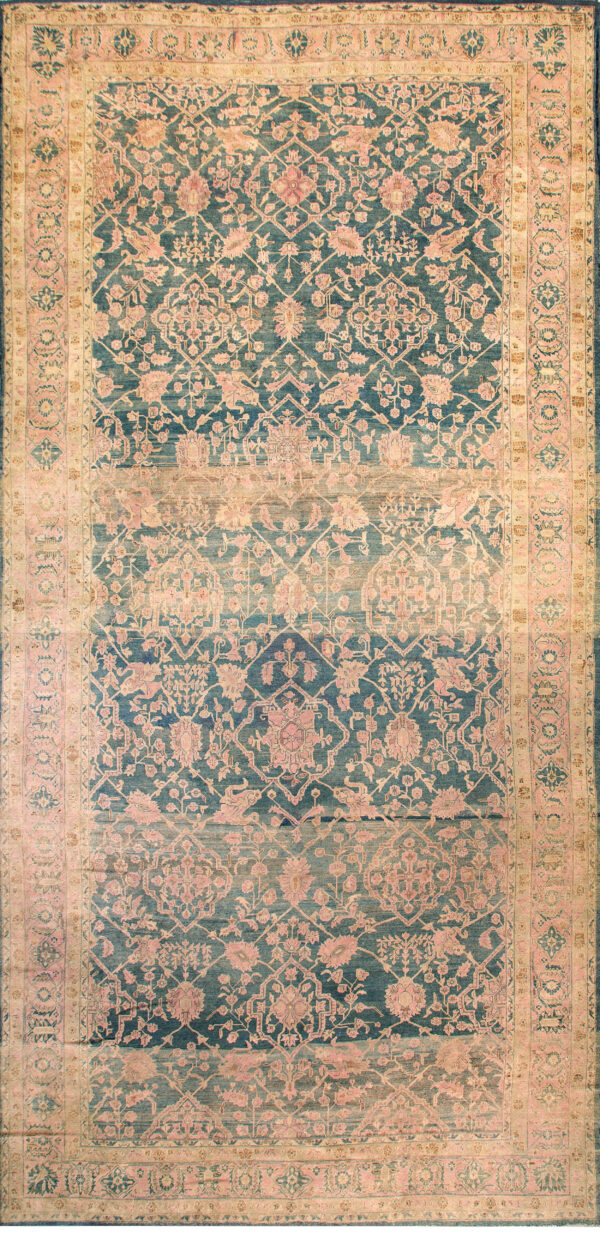 Ornate, faded blue and gold floral rug with pink accents covers a worn wooden plank floor.