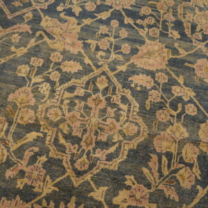 Ornate, faded blue and gold floral rug with pink accents covers a worn wooden plank floor.