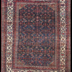 Deep navy rug featuring complex red and blue motifs with a wide stylized floral ivory border.