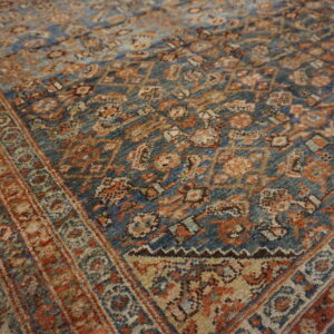 An intricate, traditional patterned rug featuring a deep blue field with rust and beige details.
