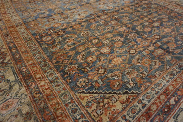 An intricate, traditional patterned rug featuring a deep blue field with rust and beige details.