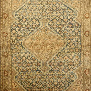 Low-pile patterned rug with intricate navy blue, tan, and rust floral motifs and a central geometric medallion.