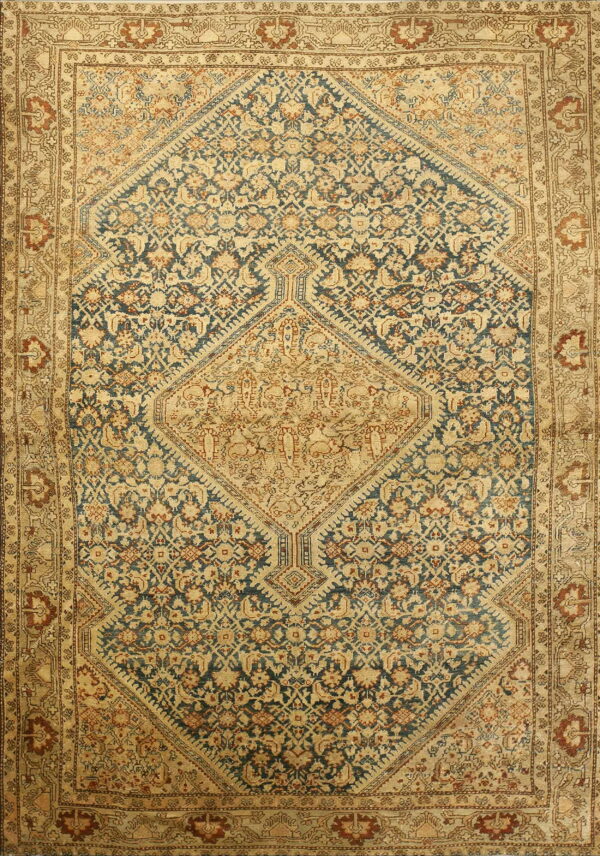 Low-pile patterned rug with intricate navy blue, tan, and rust floral motifs and a central geometric medallion.