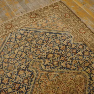 Corner view of a traditional navy and beige patterned rug on distressed wooden planks.