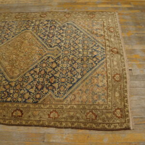 Low-pile tan and blue traditional rug with a large medallion on heavily worn wood floors.