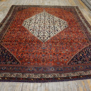 Red patterned rug with a central ivory medallion and navy corners lies on light-colored wood flooring.