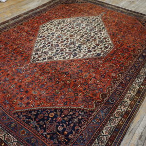Red and navy traditional rug featuring an ornate cream medallion on light wood plank flooring.