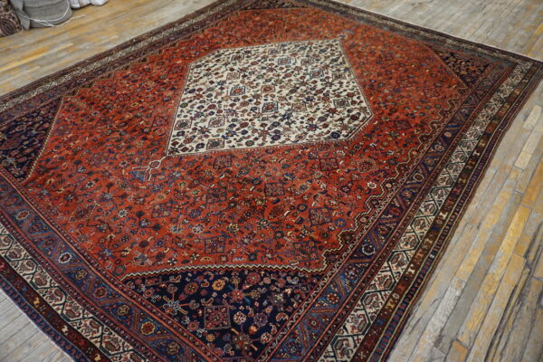 Red and navy traditional rug featuring an ornate cream medallion on light wood plank flooring.