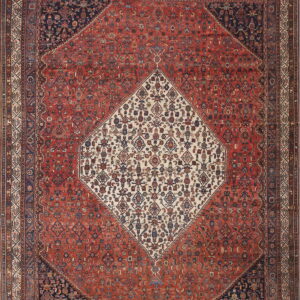 Intricate traditional rug with a red field, navy corners, and a detailed cream central diamond medallion.