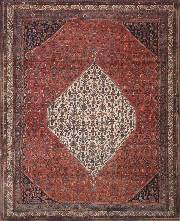Intricate traditional rug with a red field, navy corners, and a detailed cream central diamond medallion.