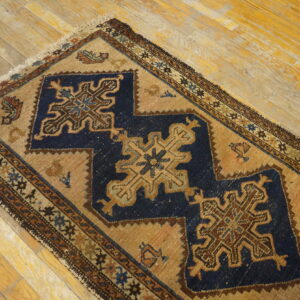 A small rug featuring navy blue and tan geometric patterns is placed on distressed wood planks.
