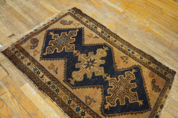 A small rug featuring navy blue and tan geometric patterns is placed on distressed wood planks.