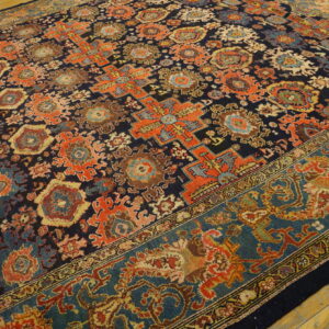 Navy rug with colorful orange, blue, and brown medallions, featuring a wide teal border on wood flooring.