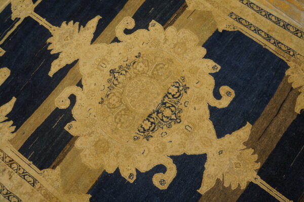Low-pile rug in deep blue and gold featuring a large ornate medallion over diagonal stripes.