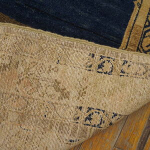 The woven tan backside of a blue and gold low pile rug is visible on wood flooring.