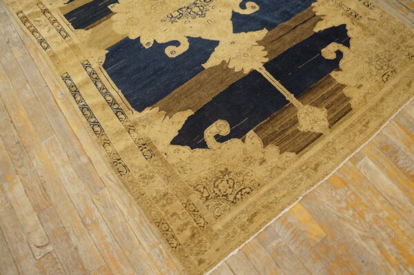 Stylized tan motifs overlay dark blue and brown stripes on a rug lying on light wood planks.