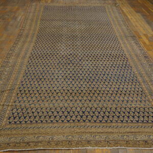 Long blue and tan patterned rug with ornate borders lies on weathered wood plank flooring.