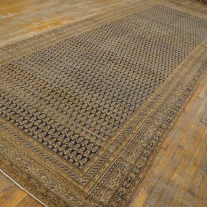 Low-pile rug with a repeating dark blue and gold pattern and complex borders on distressed wood flooring.