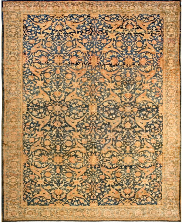 Low-pile area rug featuring ornate tan, gold, and peach floral and stylized animal designs on a dark blue ground.