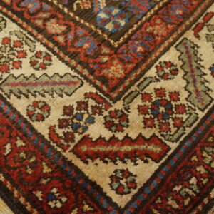 Close-up of a corner border showing traditional red, blue, and beige patterns on wood flooring.