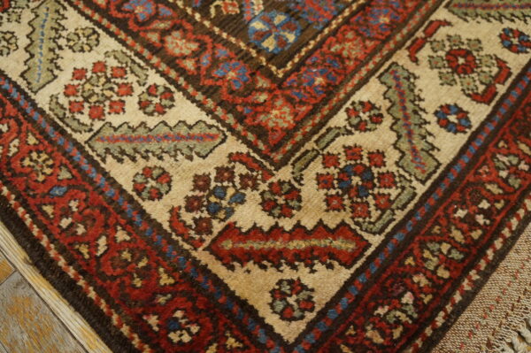 Close-up of a corner border showing traditional red, blue, and beige patterns on wood flooring.