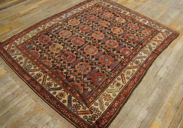 Dark geometric rug featuring red, blue, and tan medallions is placed on rustic wood floors.
