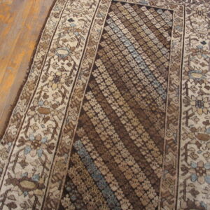 Runner rug featuring muted brown and beige colors, floral borders, and a striped geometric pattern on a wood floor.