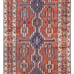 Geometric runner rug with a terracotta field, featuring repeated blue and beige tribal motifs.