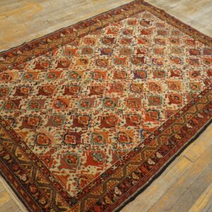 Geometric patterned rug featuring orange, red, and cream colors on rustic plank wood flooring.