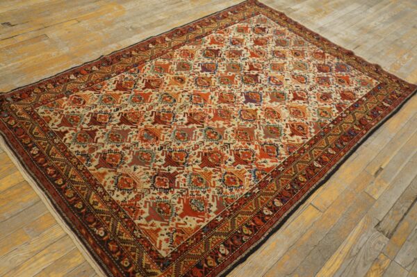 Geometric patterned rug featuring orange, red, and cream colors on rustic plank wood flooring.