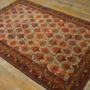 Cream rug with dense red, blue, and gold geometric motifs lays on worn wood planks.