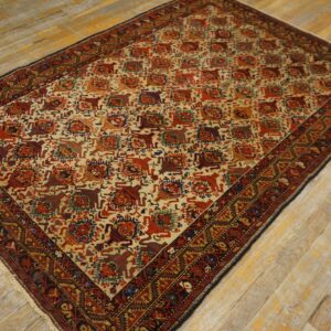 Red and cream repeating geometric pattern rug with a dark border sits on rustic wood planks.