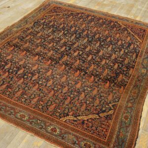 Navy area rug featuring a dense pattern of rust and teal paisleys on pale wood planks.