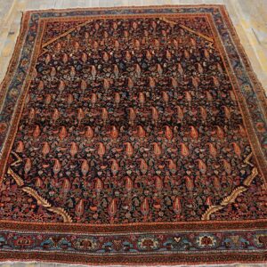 Ornate dark field rug with rust paisley motifs and teal accents rests on weathered plank flooring.