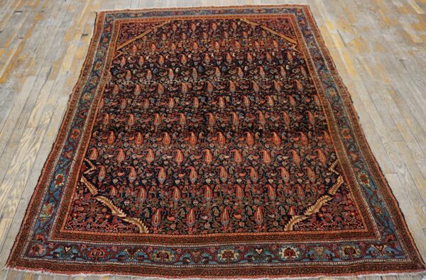 Ornate dark field rug with rust paisley motifs and teal accents rests on weathered plank flooring.