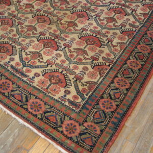 Low-pile beige rug featuring red and teal geometric floral patterns and a wide border on light wood planks.