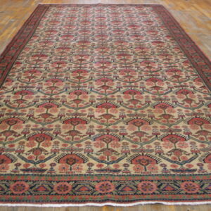Long runner rug with repeating red, pink, and blue geometric motifs on a beige field over light wood flooring.