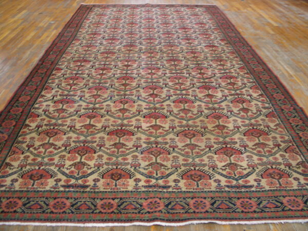 Long runner rug with repeating red, pink, and blue geometric motifs on a beige field over light wood flooring.