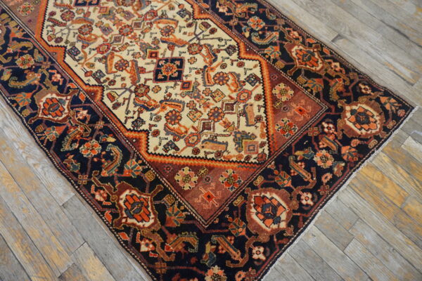 A low-pile area rug with a navy, rust, and ivory medallion pattern sits on weathered wood flooring.